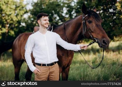guy in a white shirt on a walk with brown horses in the village