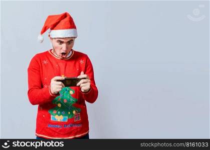 Guy in christmas hat looking at a christmas promo on phone. Surprised man watching a christmas promotion on the phone, Amazed man in christmas hat looking at a christmas special offers