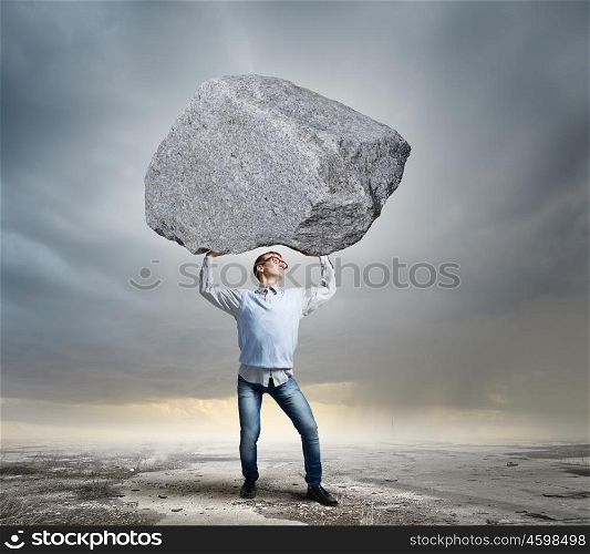 Guy lifting stone. Young strong man holding huge stone above head