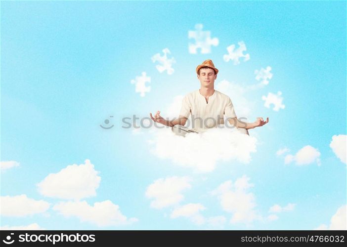 Guy meditating. Young handsome man meditating sitting on clouds