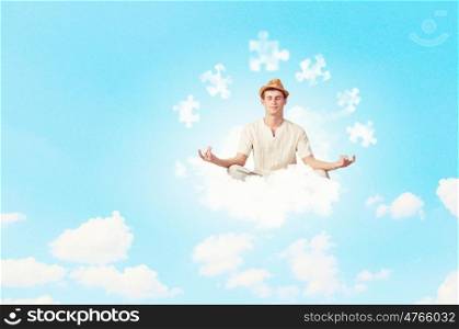 Guy meditating. Young handsome man meditating sitting on clouds