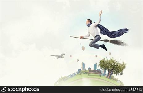 Guy on broom. Young businessman flying on broom high in sky