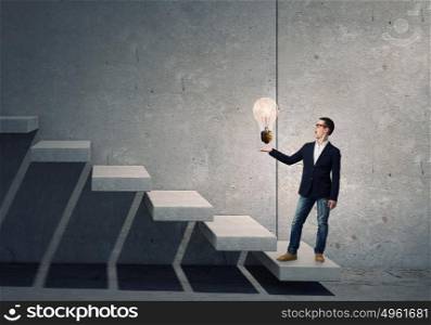 Guy presenting bright idea. Young student guy in jacket showing light bulb in palm