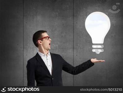 Guy presenting bright idea. Young student guy in jacket showing light bulb in palm