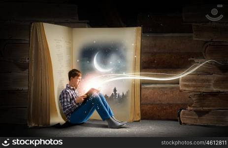Guy reading book. Teenager boy wearing jeans and shirt and reading book