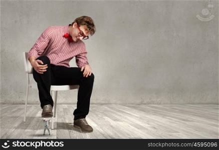 Guy sitting on chair and stepping on small business person. I will smash you
