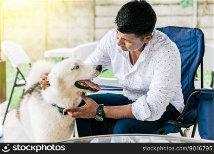 Guy sitting playing with his husky dog. Young man sitting petting his dog in the backyard. Concept of person petting his husky dog