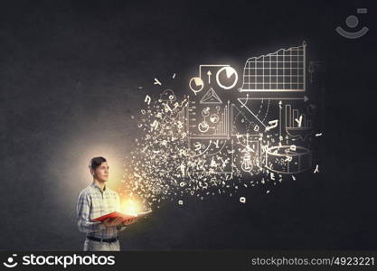 Guy studying finances. Young man with opened book in hands and infographs on wall