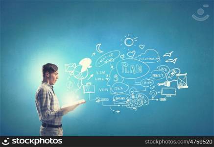 Guy studying planning and strategy concepts. Young businessman with opened book in hands on blue background