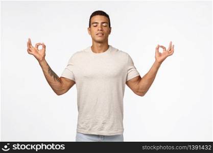Guy trying find peace in meditation. Musculine handsome young man close eyes, breathe relaxed and patient, spread hands sideways in zen, lotus pose, reach nirvana, practice yoga, white background.. Guy trying find peace in meditation. Musculine handsome young man close eyes, breathe relaxed and patient, spread hands sideways in zen, lotus pose, reach nirvana, practice yoga, white background