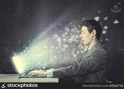 Guy using laptop. Thoughtful young man in suit seriously looking in laptop