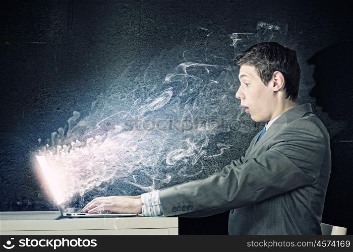 Guy using laptop. Young man in suit looking astonished in laptop. Surfing the internet
