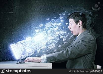 Guy using laptop. Young man in suit looking astonished in laptop. Surfing the internet