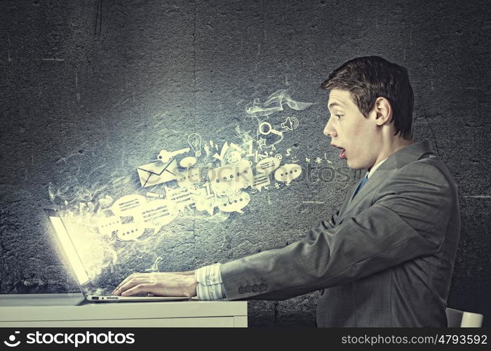 Guy using laptop. Young man in suit looking astonished in laptop. Surfing the internet