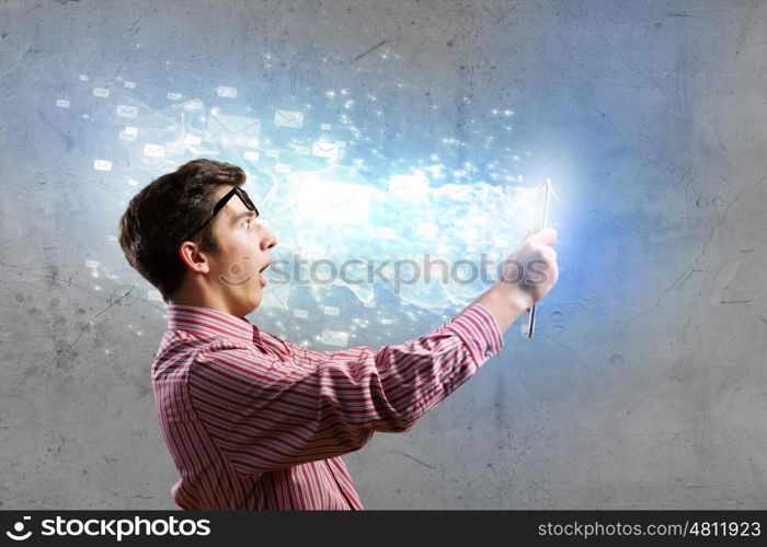 Guy using tablet pc. Young man looking shocked in tablet pc