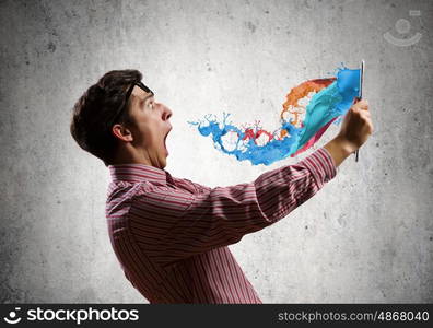 Guy using tablet pc. Young man looking shocked in tablet pc