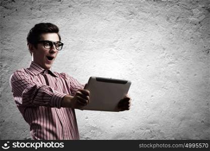 Guy using tablet pc. Young man looking shocked in tablet pc
