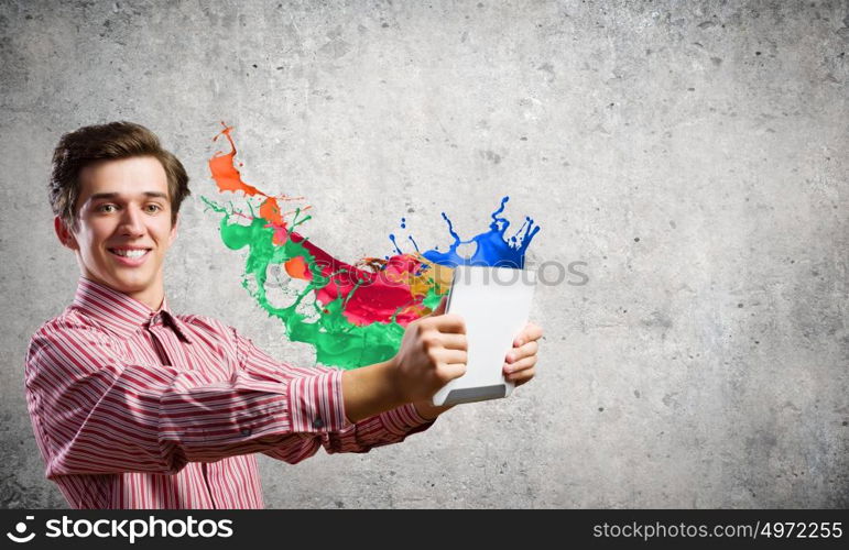 Guy using tablet pc. Young smiling man with tablet pc in hands