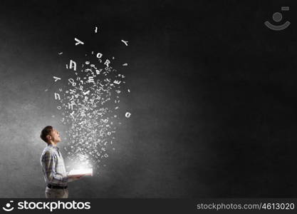 Guy with book in hands. Close view of man with opened book in hands and characters flying in air