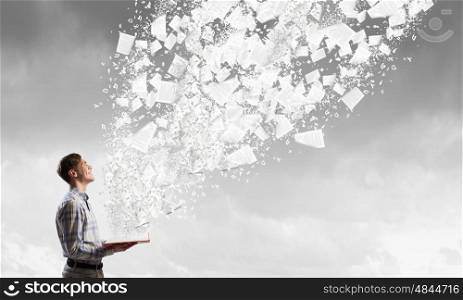 Guy with book in hands. Young businessman with opened book in hands and pages flying in air