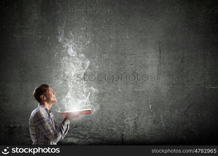 Guy with book in hands. Young man with book in hands and light coming from pages
