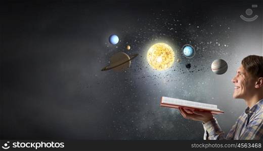 Guy with book in hands. Young man with opened book and planets of space spinning around