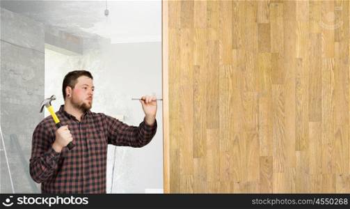 Guy with construction tools. Casual man in checked shirt indoors with hammer and nails