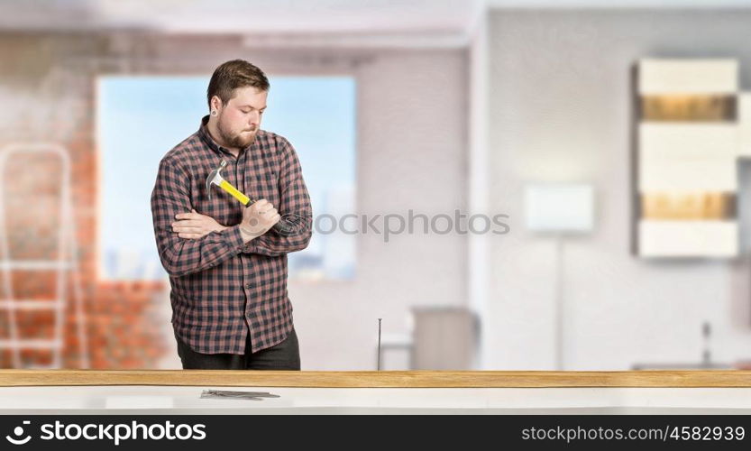 Guy with construction tools. Casual man in checked shirt indoors with hammer and nails