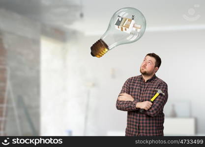 Guy with construction tools. Casual man in checked shirt indoors with hammer and nails