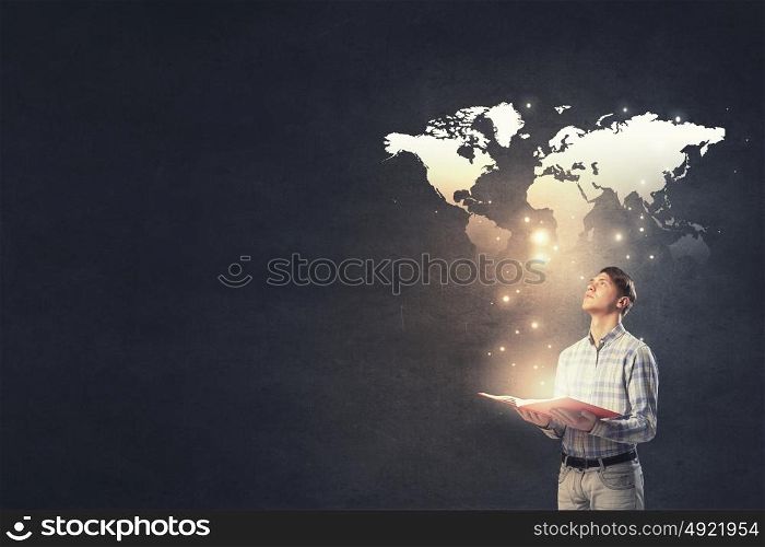 Guy with glowing book. Young businessman with opened book in hands and world map on background