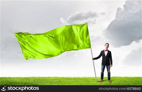 Guy with green flag. Young man in bowtie with green waving flag on stick
