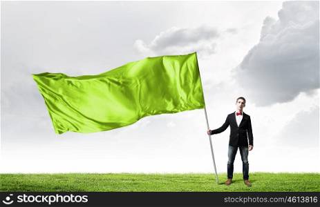 Guy with green flag. Young man in bowtie with green waving flag on stick