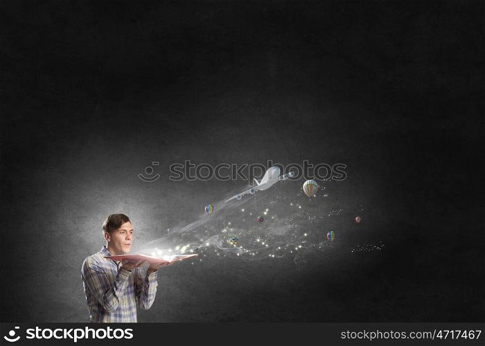 Guy with opened book. Young businessman with opened book in hands blowing on pages