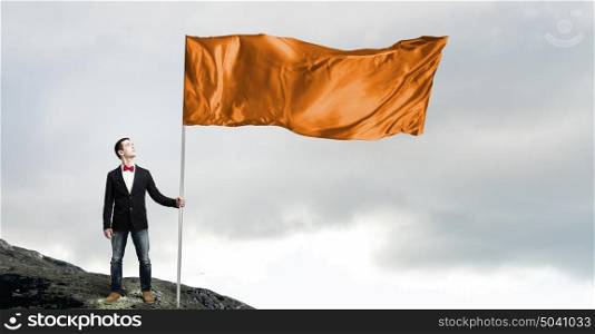 Guy with orange flag. Young man in bowtie with orange waving flag on stick