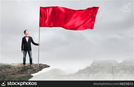Guy with red flag. Young man in bowtie with red waving flag on stick