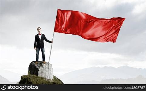 Guy with red flag. Young man in bowtie with red waving flag on stick