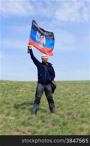 Guy with the flag DPR in the tulip field, Rostov region, Russia.