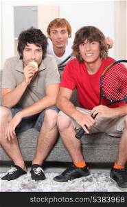 Guys sitting on sofa with tennis rackets