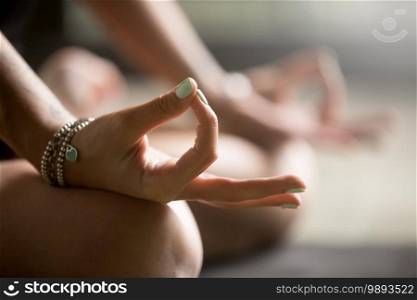 Gyan mudra close up, woman joining together the tip of index finger with thumb, wearing wrist bracelets, practicing yoga in concentration pose, stress relieve exercise at home, focus on right hand. Gyan mudra close up image