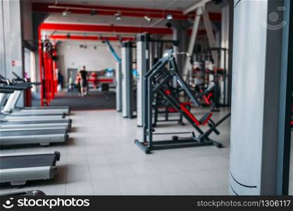 Gym interior, nobody, exersice machines and sport equipment in fitness club