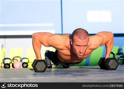 Gym man push-up strength pushup exercise with dumbbell in a crossfit workout