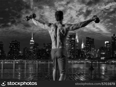 gym man rising hex dumbbells in New York city skyline at night rear view photo mount