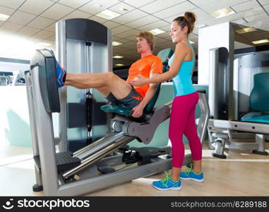 Gym seated leg press machine blond man workout and personal trainer woman