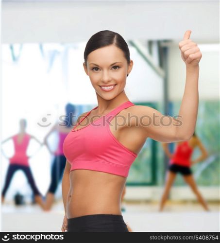 gym, sport and training concept - beautiful sporty woman showing thumbs up