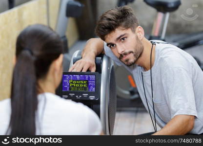 gym training instructor guiding client on using the equipment