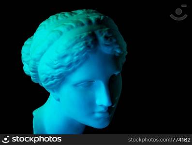 Gypsum copy of ancient statue of Venus de Milo head for artists isolated on a black background. Plaster sculpture of woman face. Blue green toned.. Gypsum copy of ancient statue Venus head isolated on a black background. Plaster sculpture woman face. Blue toned.