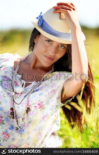 Gypsy girl with hat standing in field of wild flowers