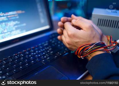 Hacker hands tied with wires, darknet using concept, information crime. Internet spy, crime lifestyle, risk job, network criminal