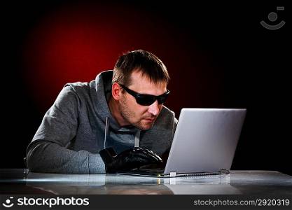 Hacker in a sunglasses with laptop.