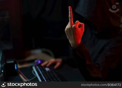 Hacker in hoodie showing middle finger and typing code to hacking programming system or server.